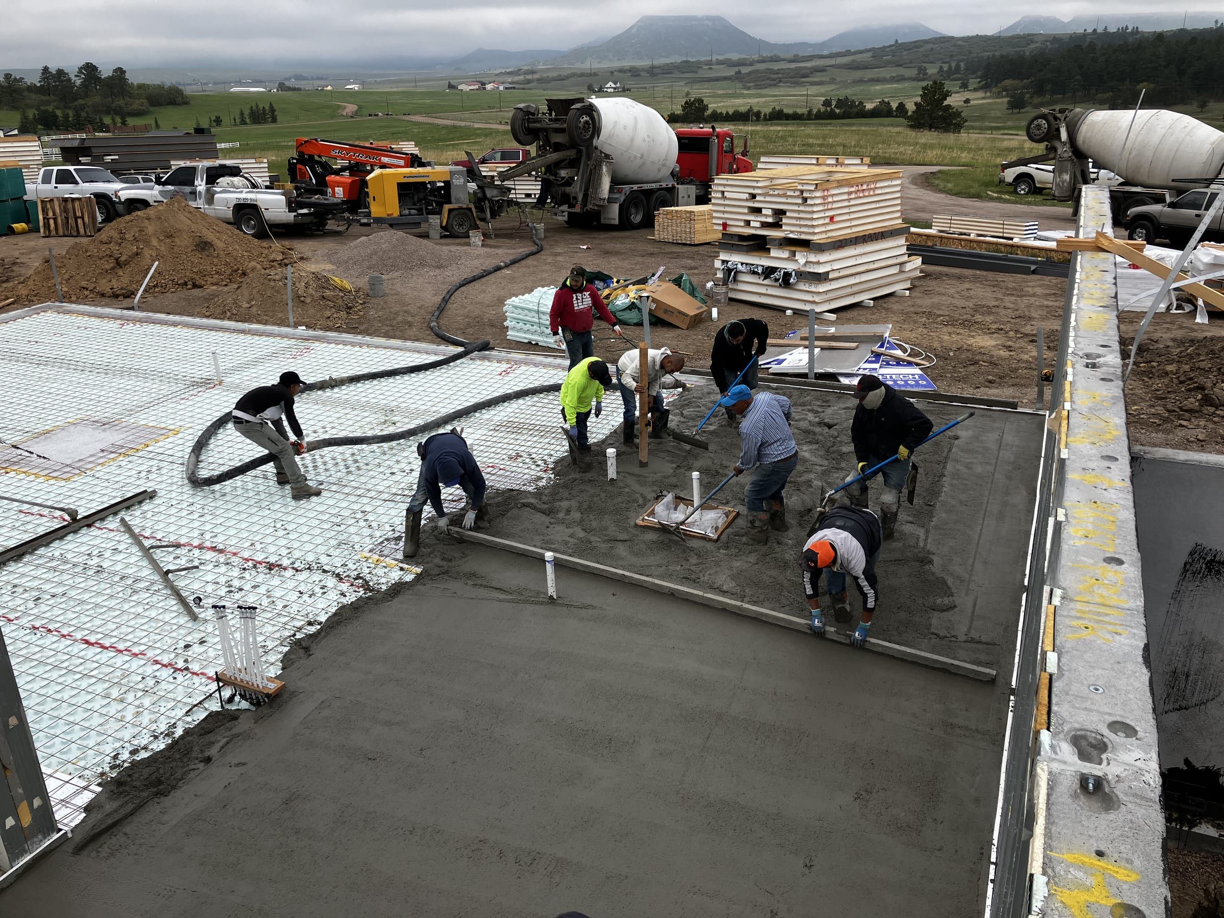 Crew placing and finishing a concrete slab over insulation